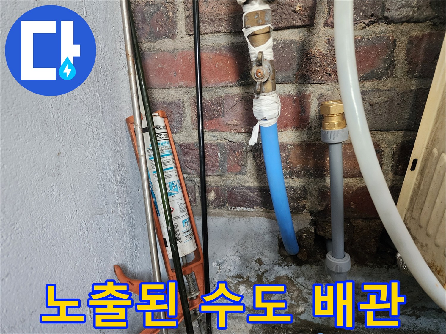 벽돌 벽면에 노출되어 물이 새고 있는 파란색 배관