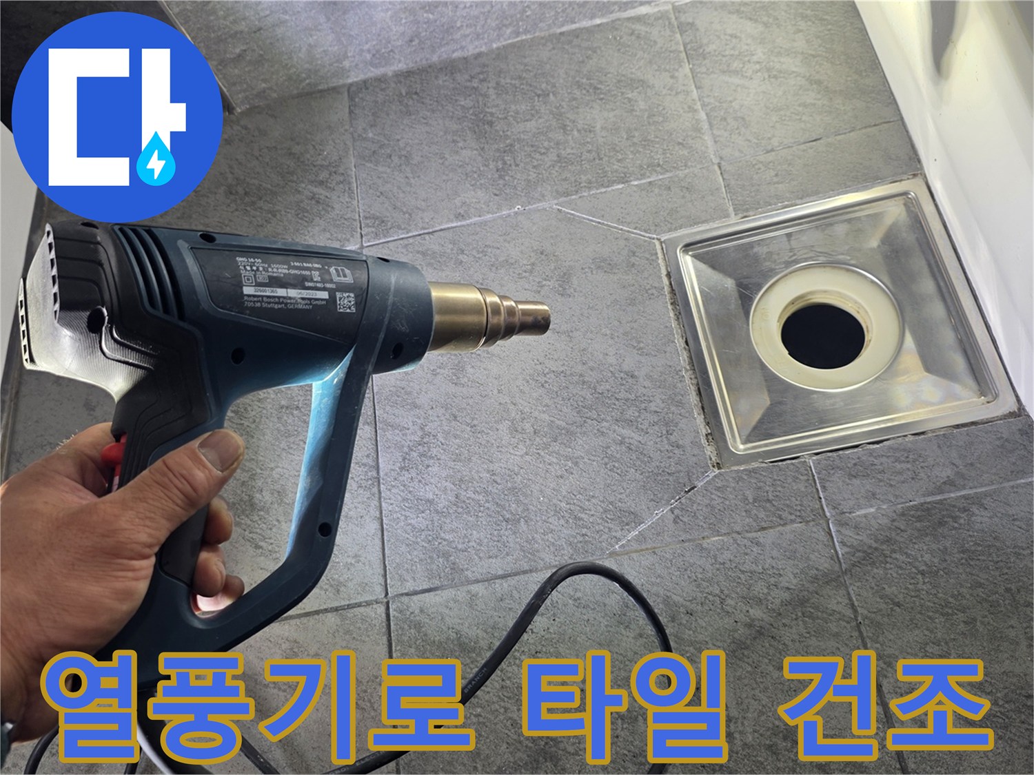 배수구 주변 타일의 습기를 열풍기로 말리는 중