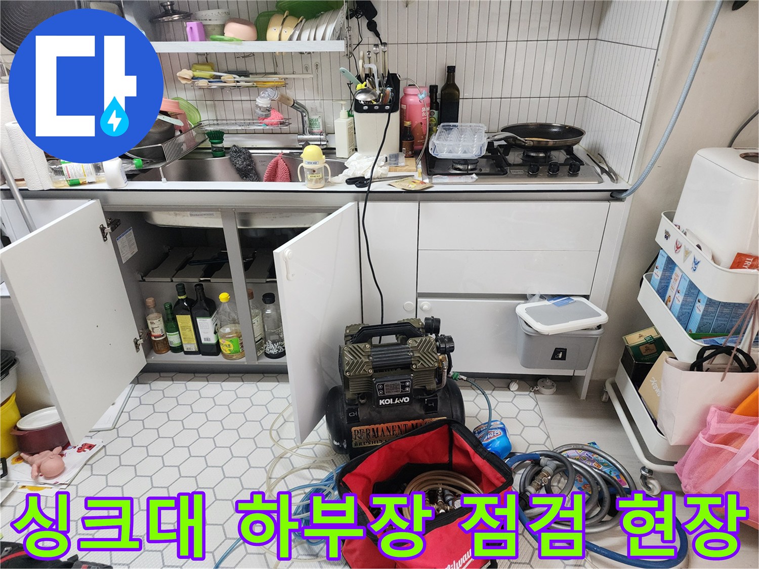 주방 싱크대 아래 하부장 내부와 점검 장비가 놓인 모습