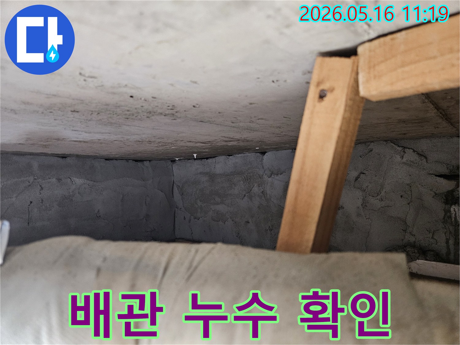 콘크리트-구조물-아래-배관과-목재-지지대가-보이는-누수-현장-사진