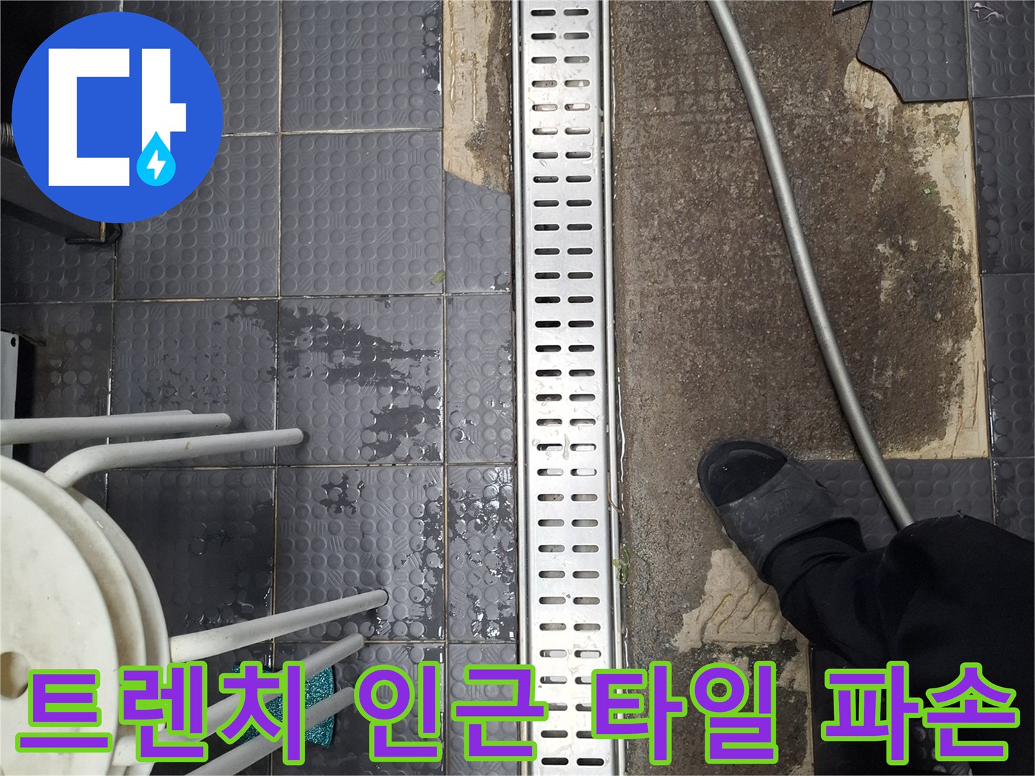 주방 배수 트렌치 옆으로 드러난 젖은 바닥과 깨진 타일 조각