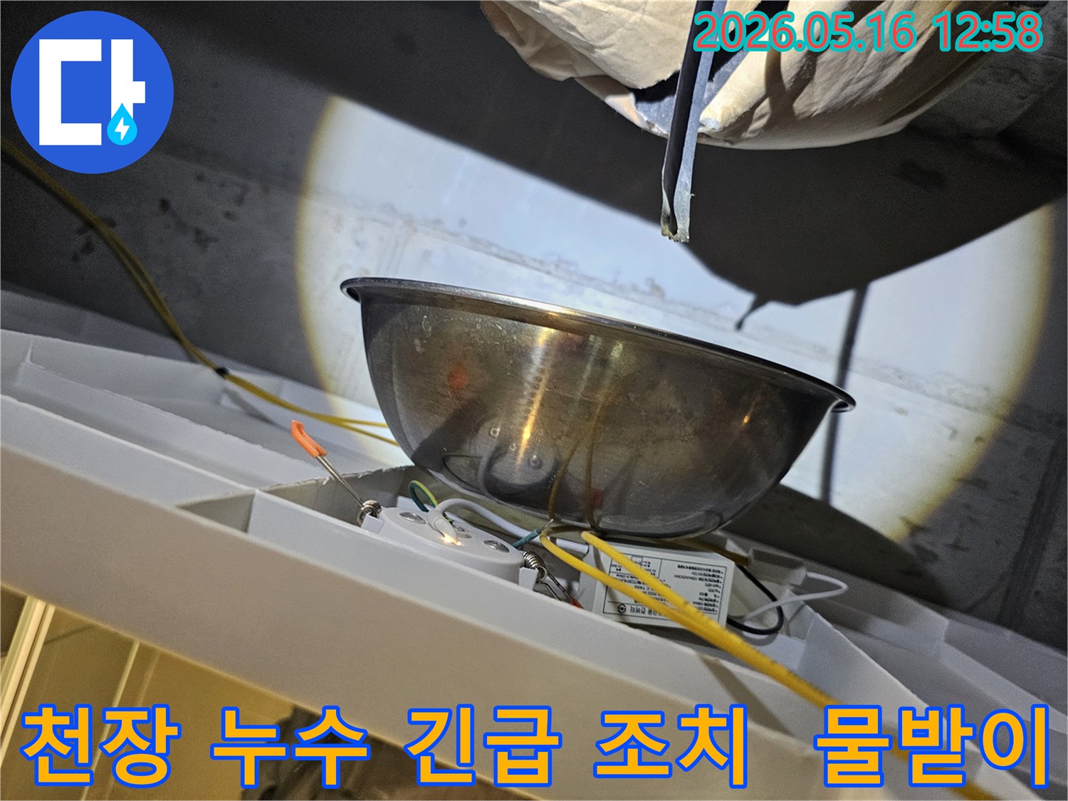 천장에서 물이 떨어지는 것을-스테인리스 볼로-받아내며-주변의 전기 배선과-조명 장치를-보호하는 긴급 조치 현장