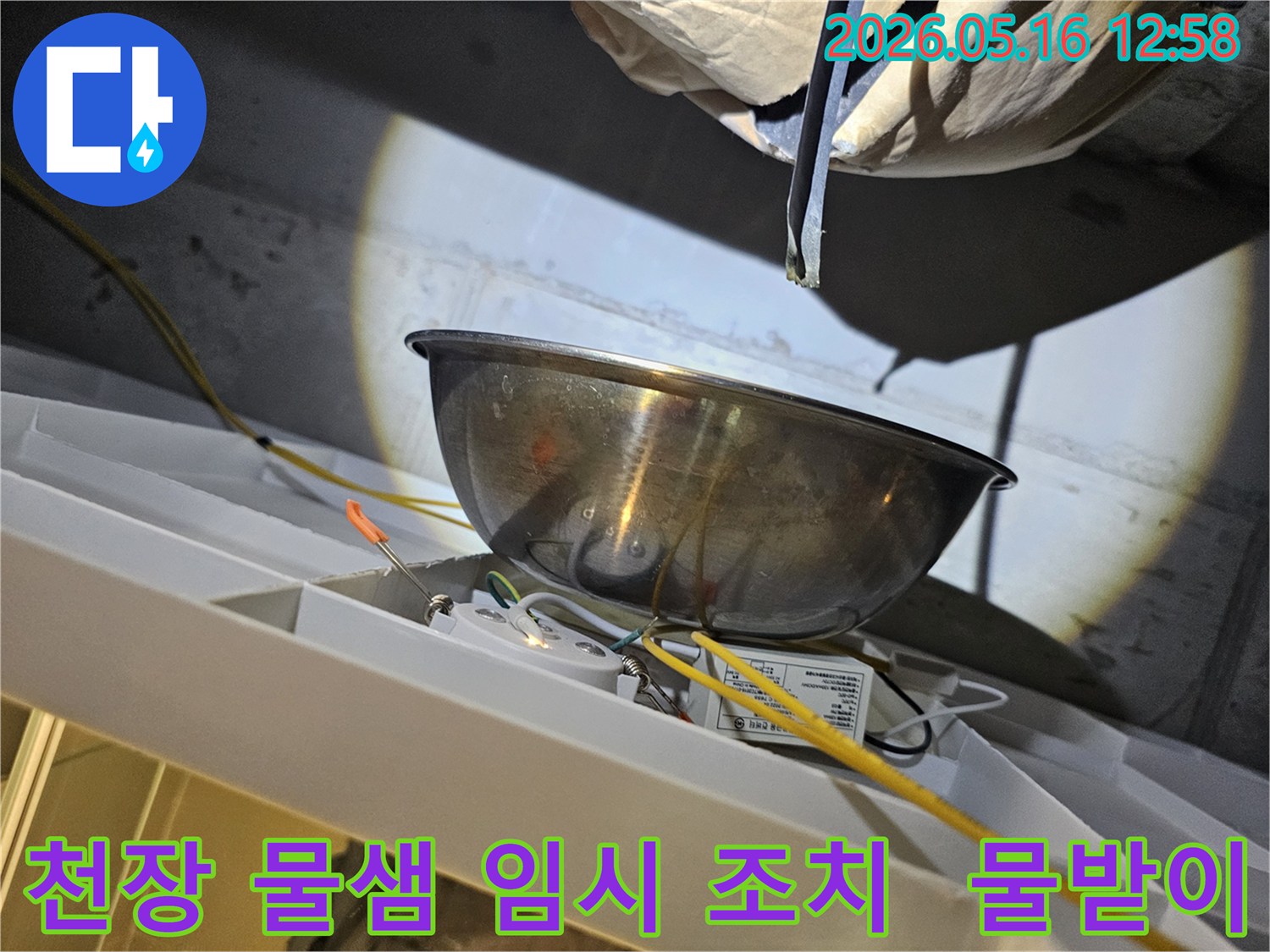 천장에서 물이 새는 것을-스테인리스 그릇으로-받아내며-전기 배선과-조명 장치 주변의-안전 상태를-점검하는 모습