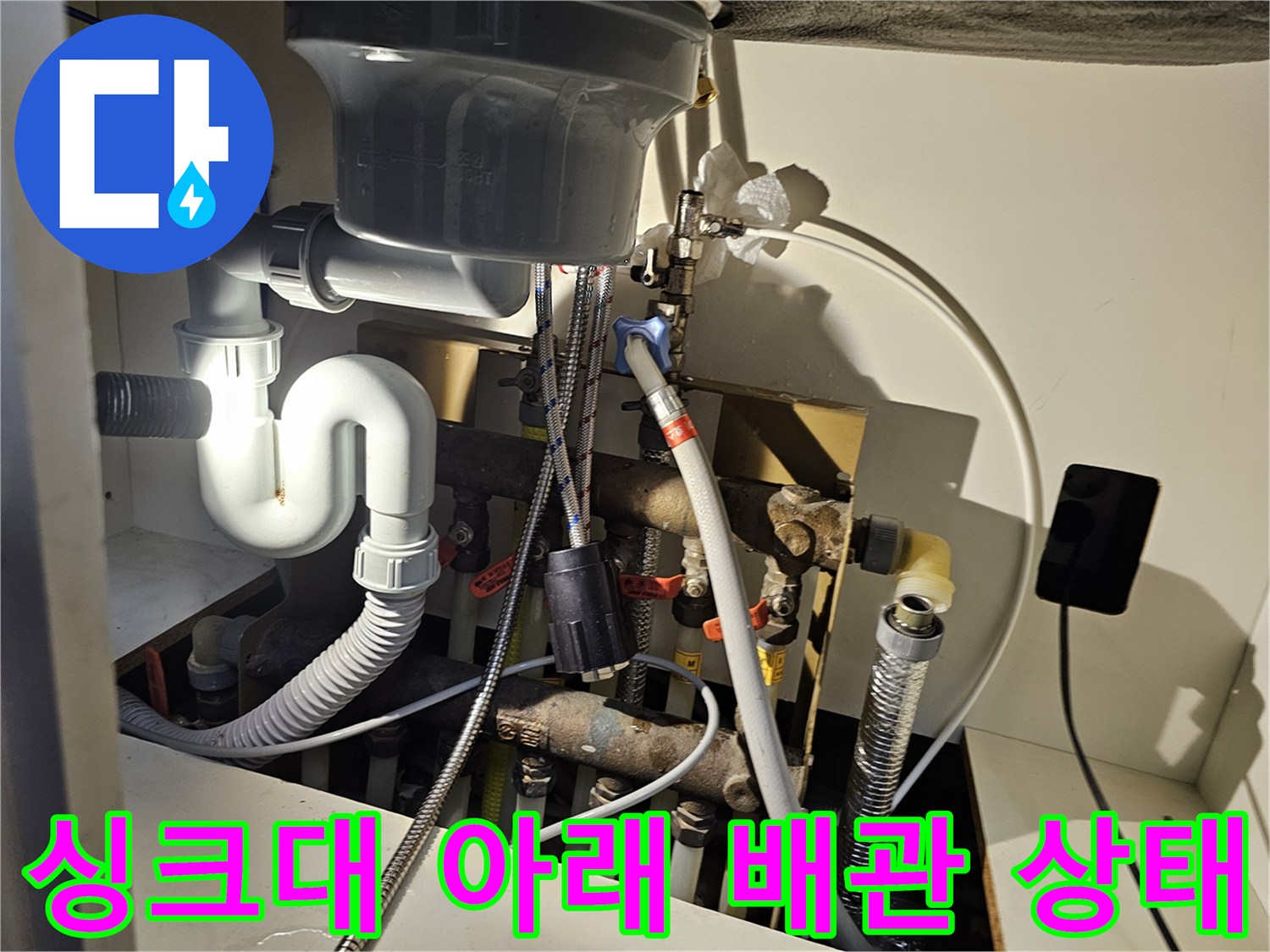 주방 싱크대 하단의 급수 및 배수 배관 연결 상세 모습
