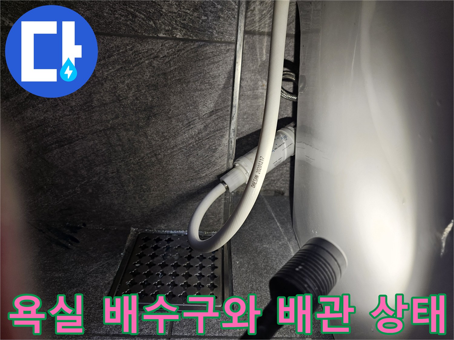 변기 옆 급수 호스와 바닥 타일 배수구 근접 촬영