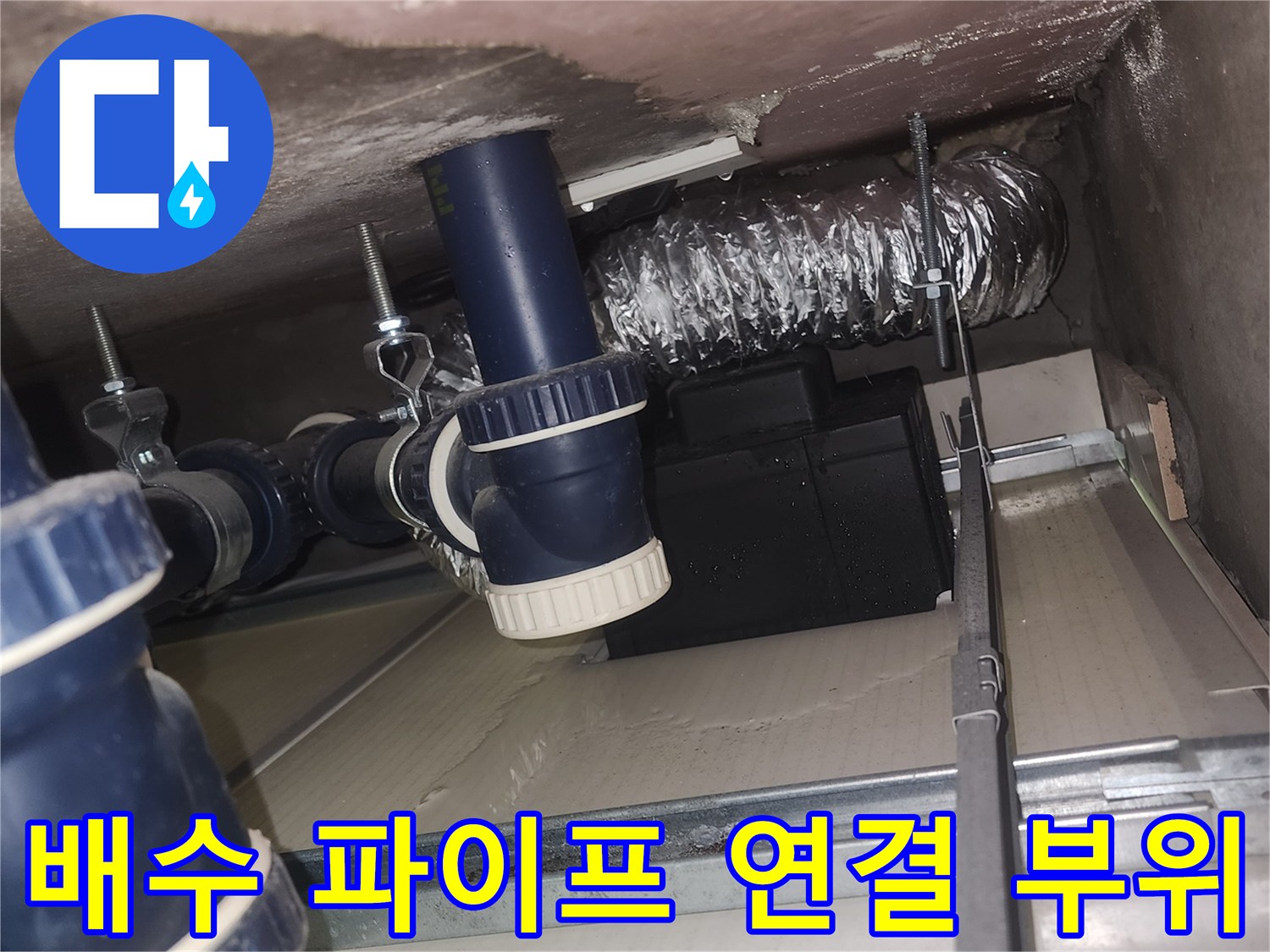 천장 내부의 파란색 배수 부속과 은색 보온재가 감겨 있는 배관 모습