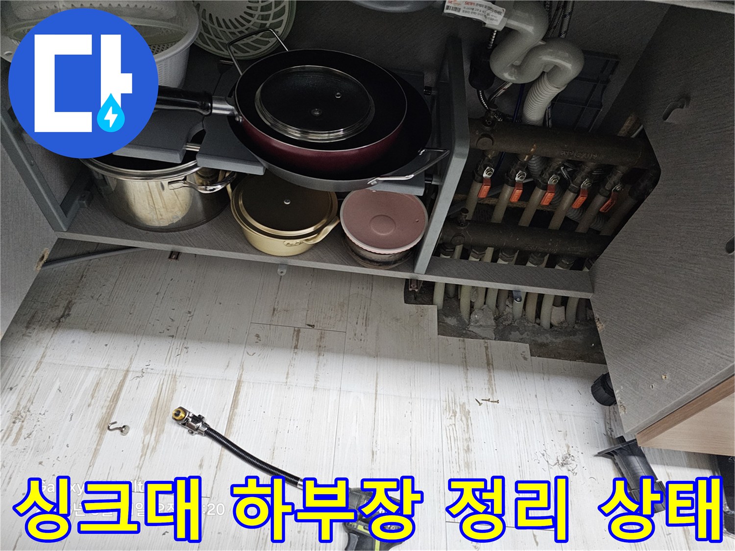 누수 점검을 위해 싱크대 하부장 내부 물건들을 모두 꺼내어 작업 공간을 확보한 모습입니다.