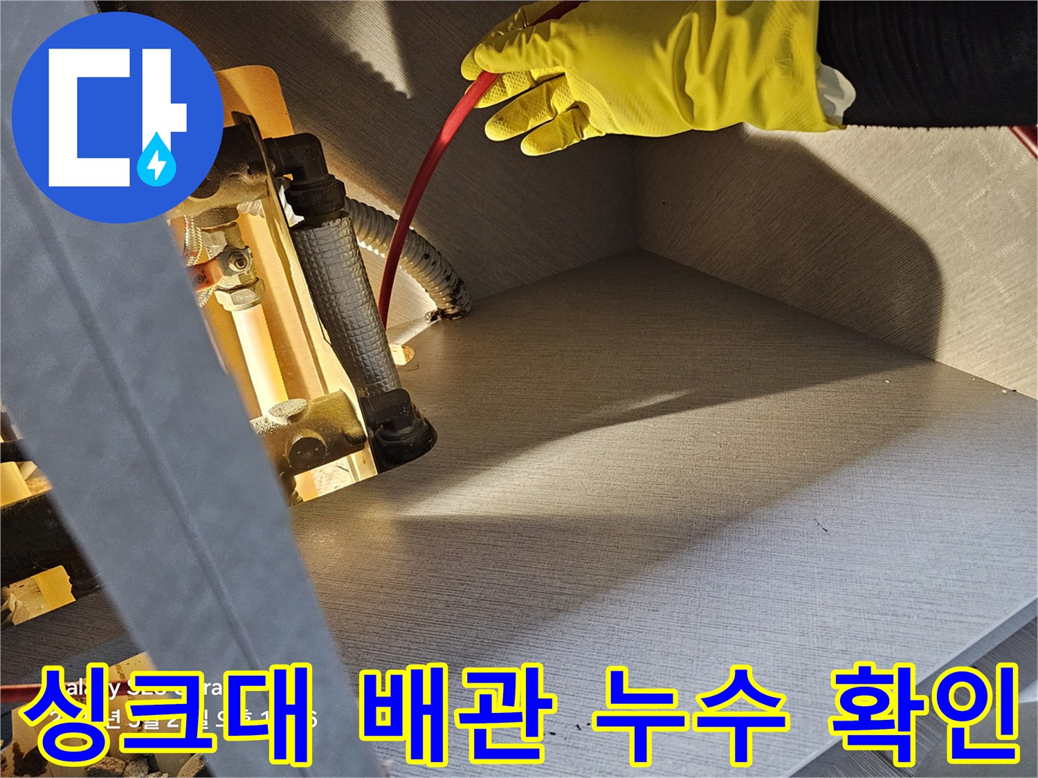 작업자가 붉은색 호스와 은색 배관이 만나는 지점을 점검하고 있습니다.