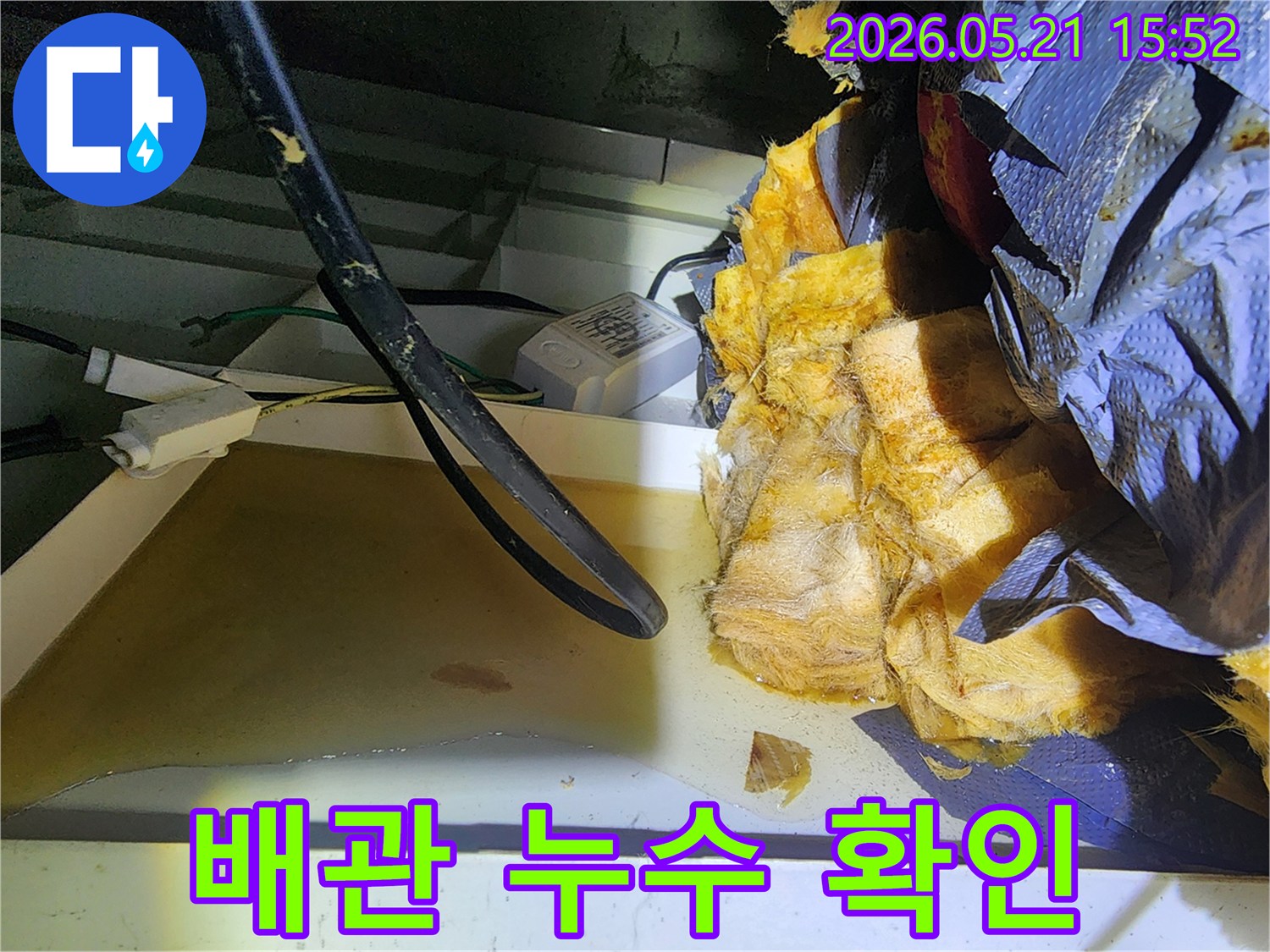 천장 내부의 젖은 단열재 주변에-위치한 배관의 상태를-점검하며 누수 원인을-파악하는 현장 사진입니다