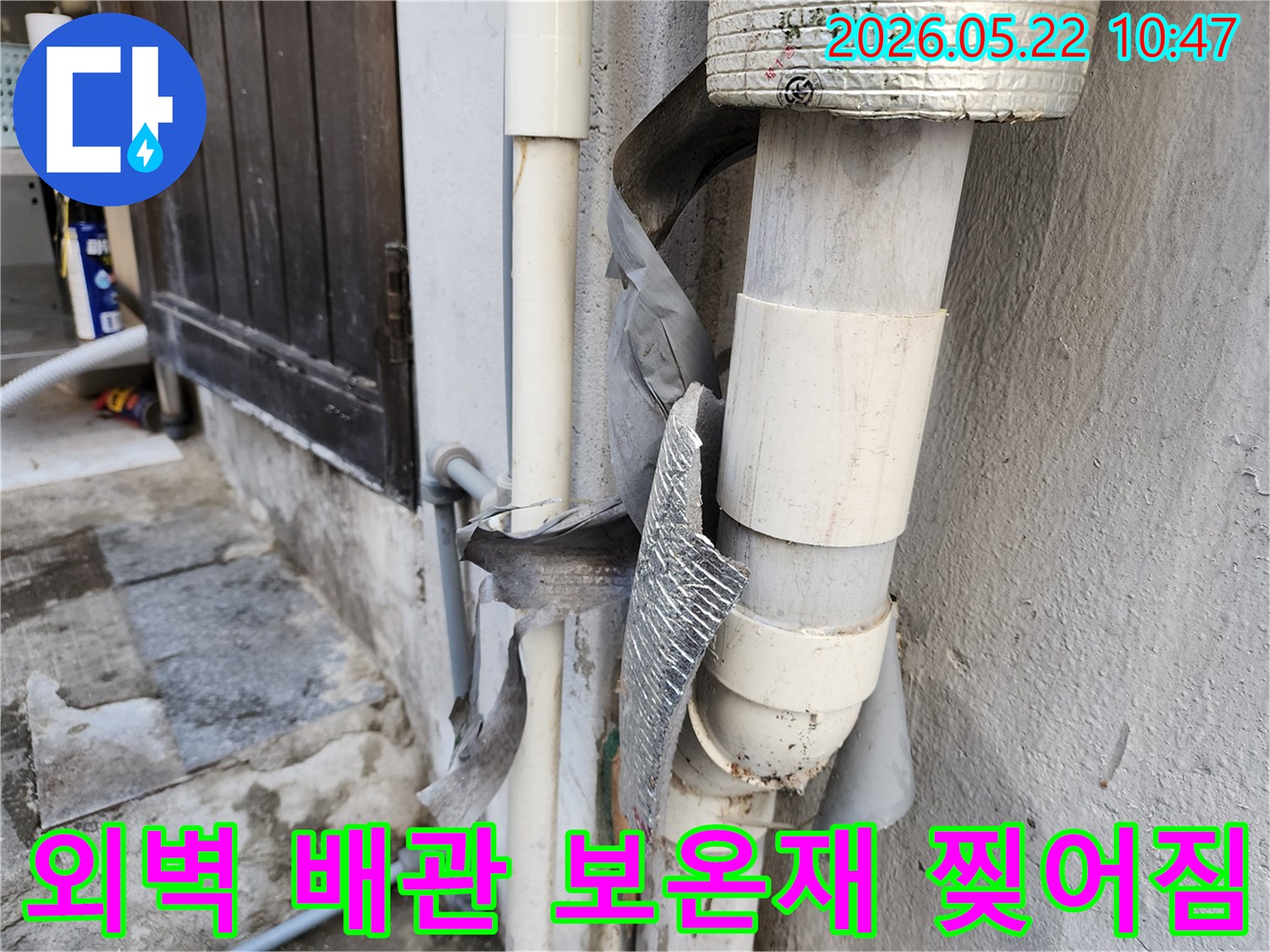 건물 외벽 배관의 보온재가 찢어져-내부 배관이 그대로 노출되어-손상 위험이 커진 모습입니다.