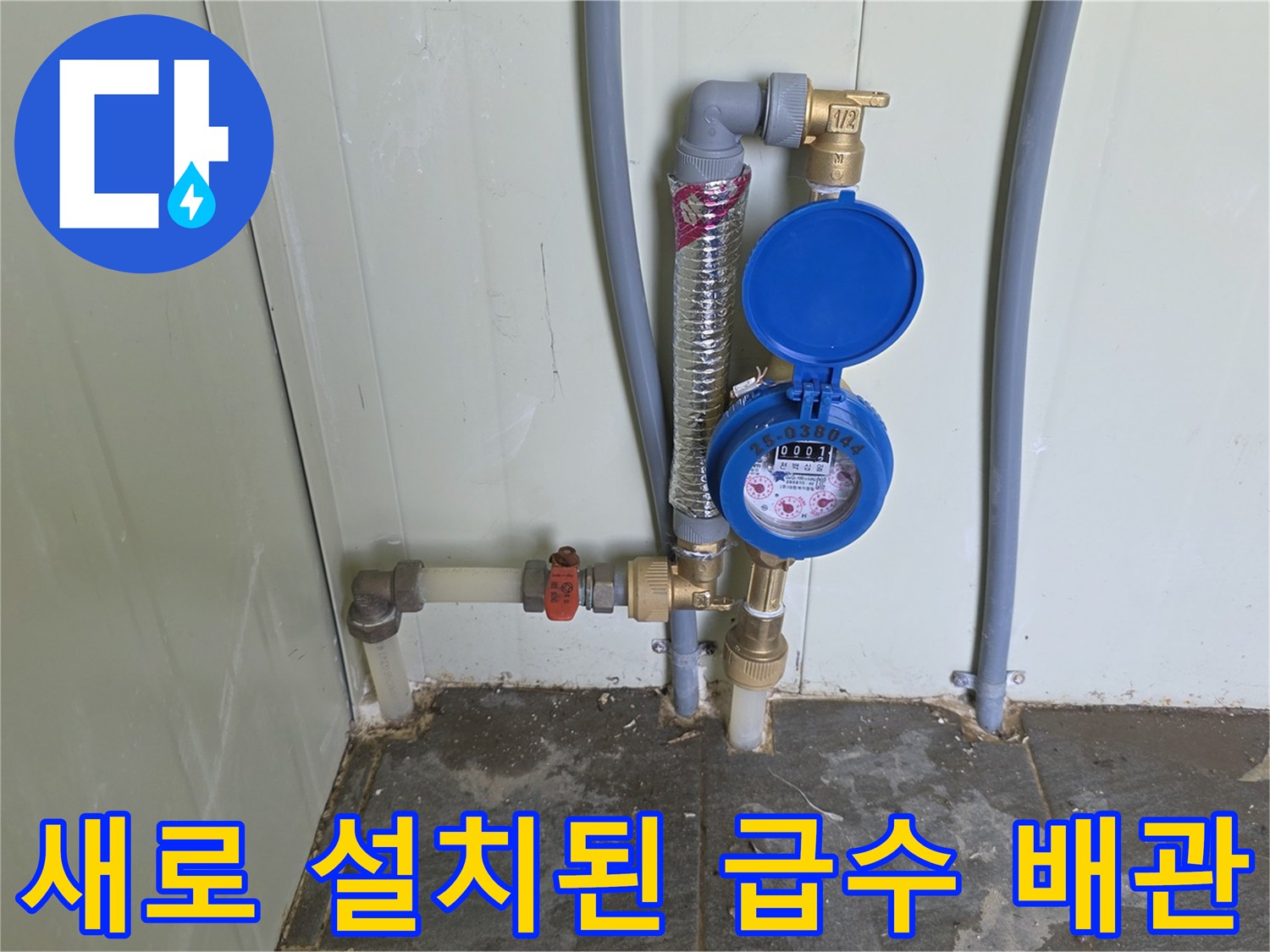 금색 부속과 파란 계량기가 결합된 급수 배관의 상세 사진입니다.