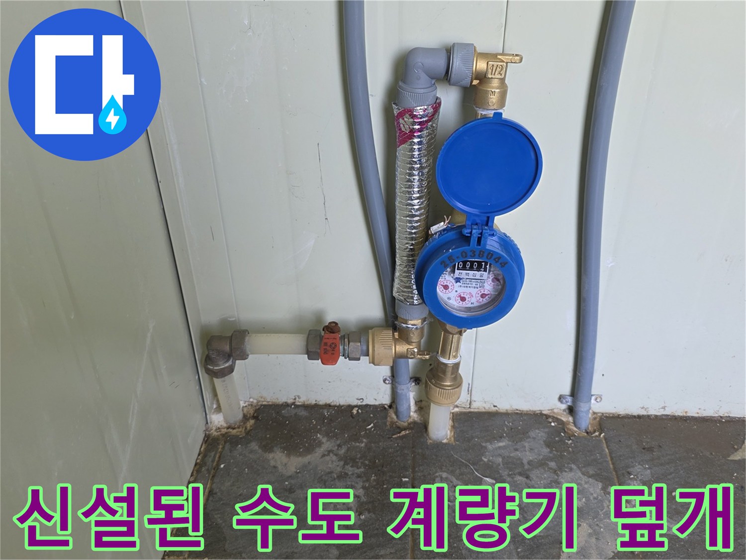 벽면 배관에 연결되어 설치 완료된 파란색 수도 계량기 장치