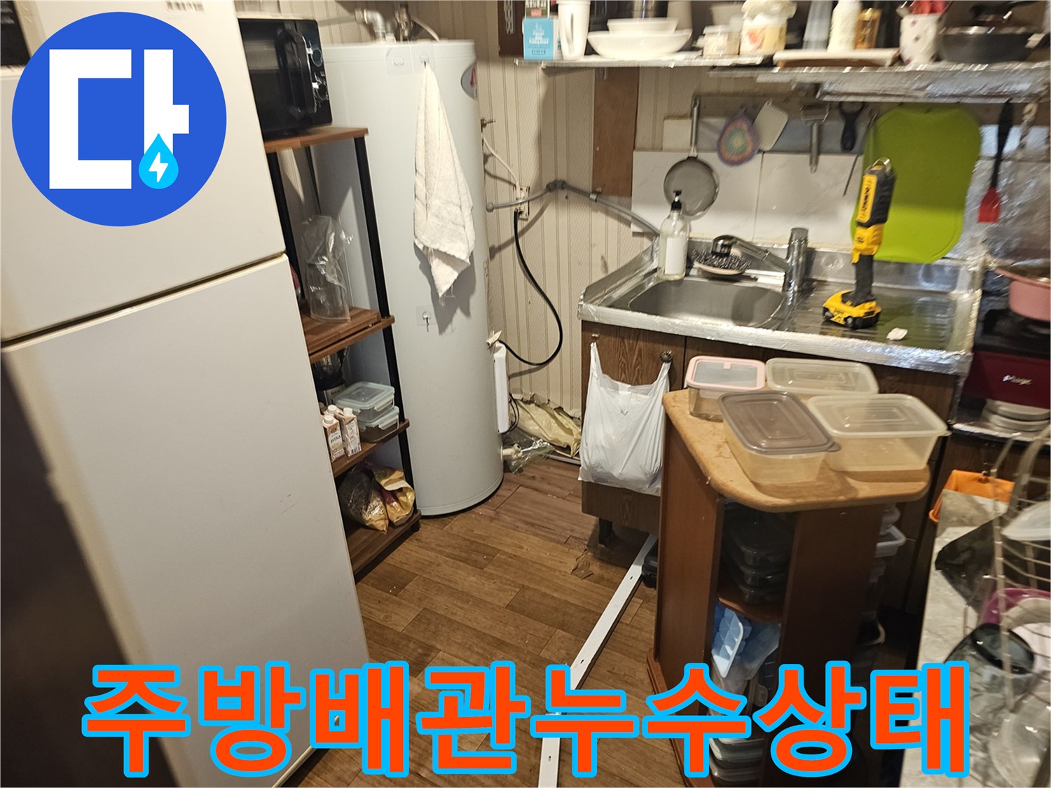 주방 싱크대 옆 온수 탱크 주변의 배관 연결 상태를 촬영한 사진