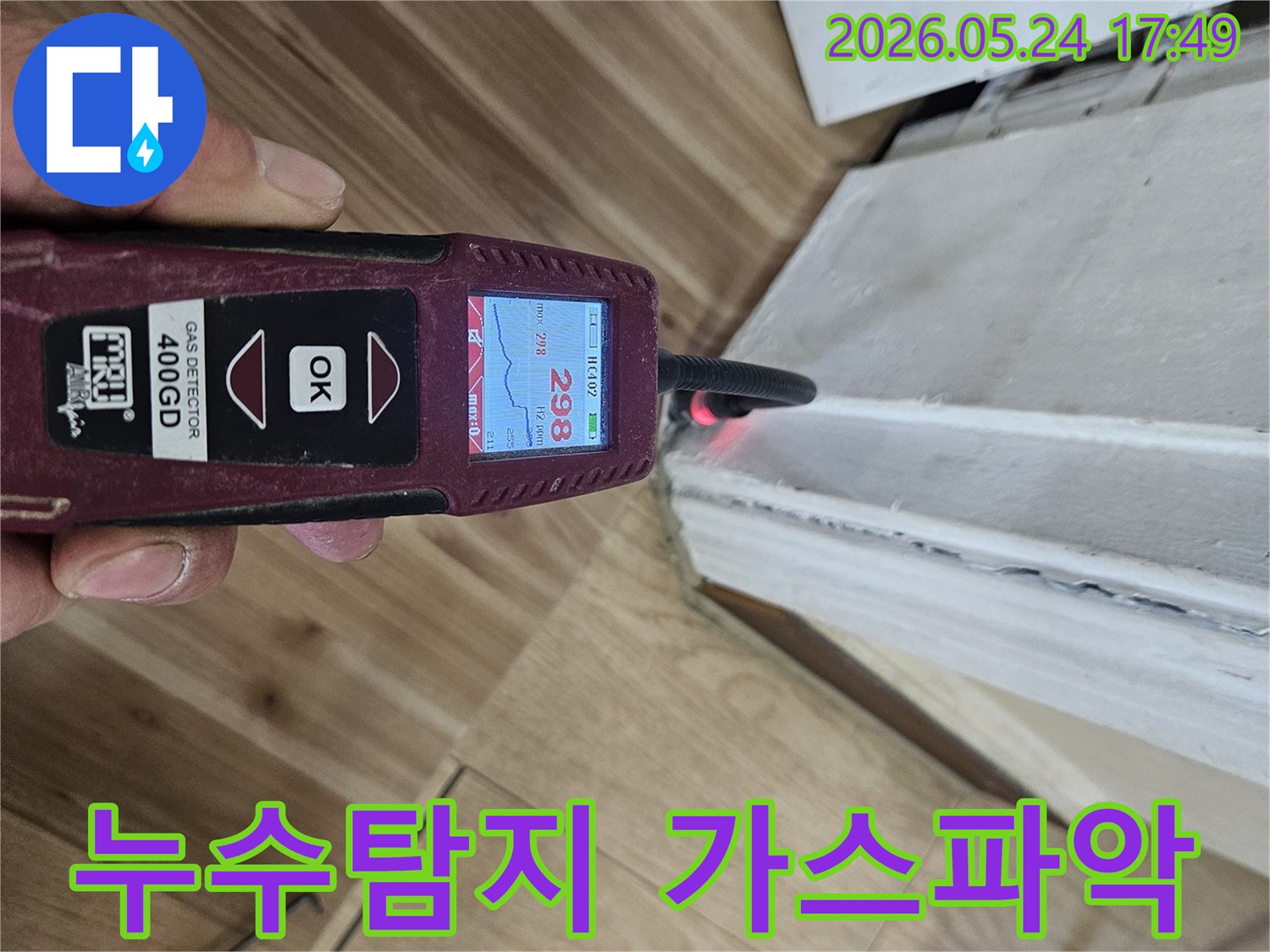 누수 엔지니어가 가스 탐지기를 사용하여 벽면과 바닥 경계에서 누수 반응을 정밀하게 확인하고 있습니다.