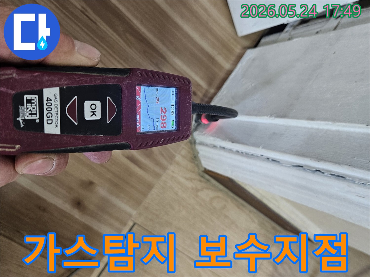 숙련된 누수 엔지니어가 가스 탐지기를 사용하여 벽면 하단에서 누수 반응을 면밀히 확인하고 있습니다.