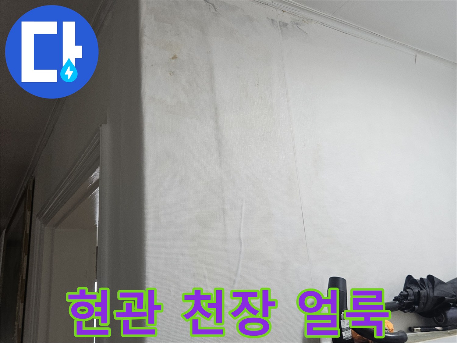 아랫집 현관 천장에 발생한 누수 흔적과 벽지 변색 상태입니다.