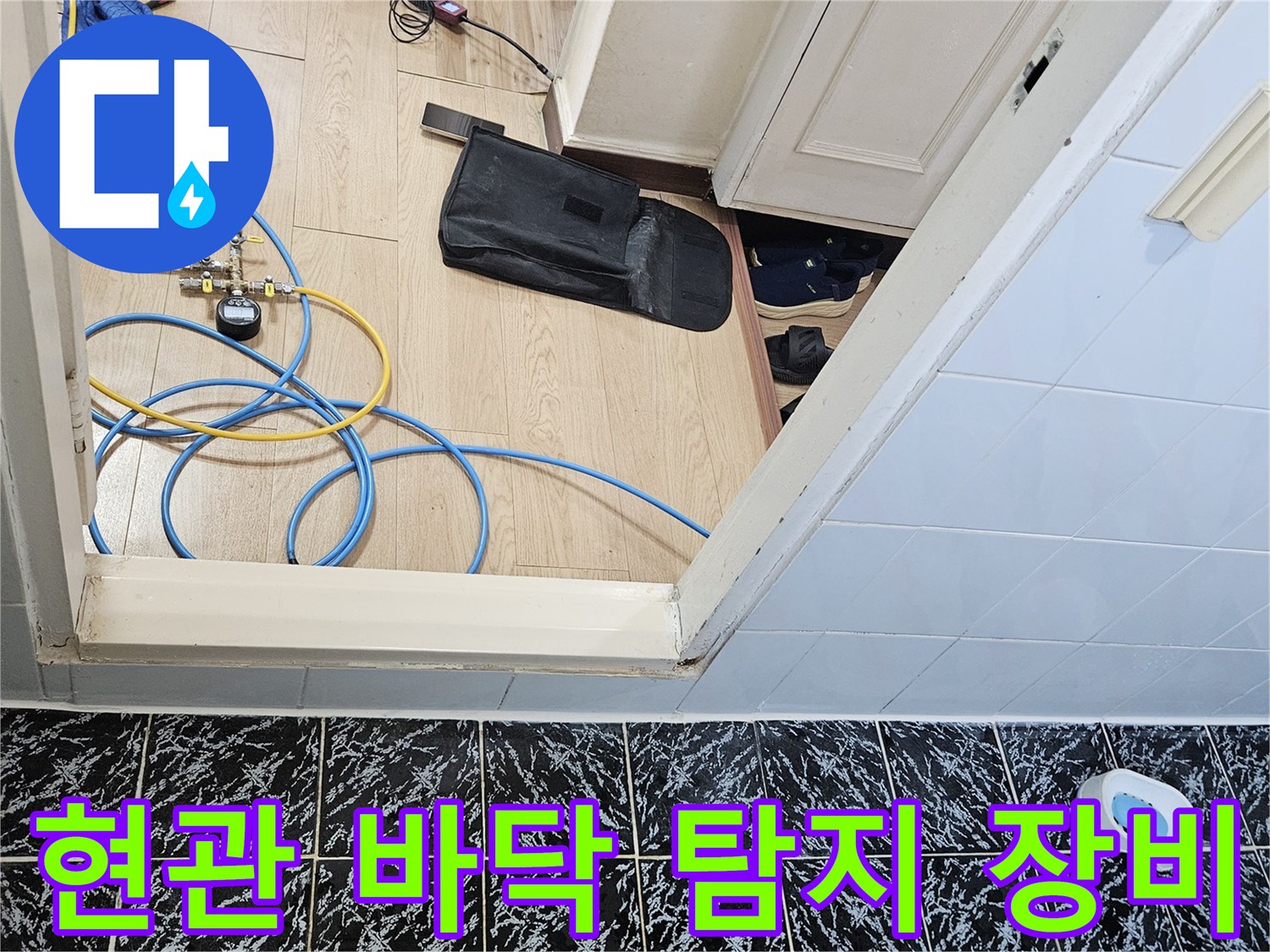 현관 타일 바닥에 배치된 가스 탐지기 및 배관 점검용 호스