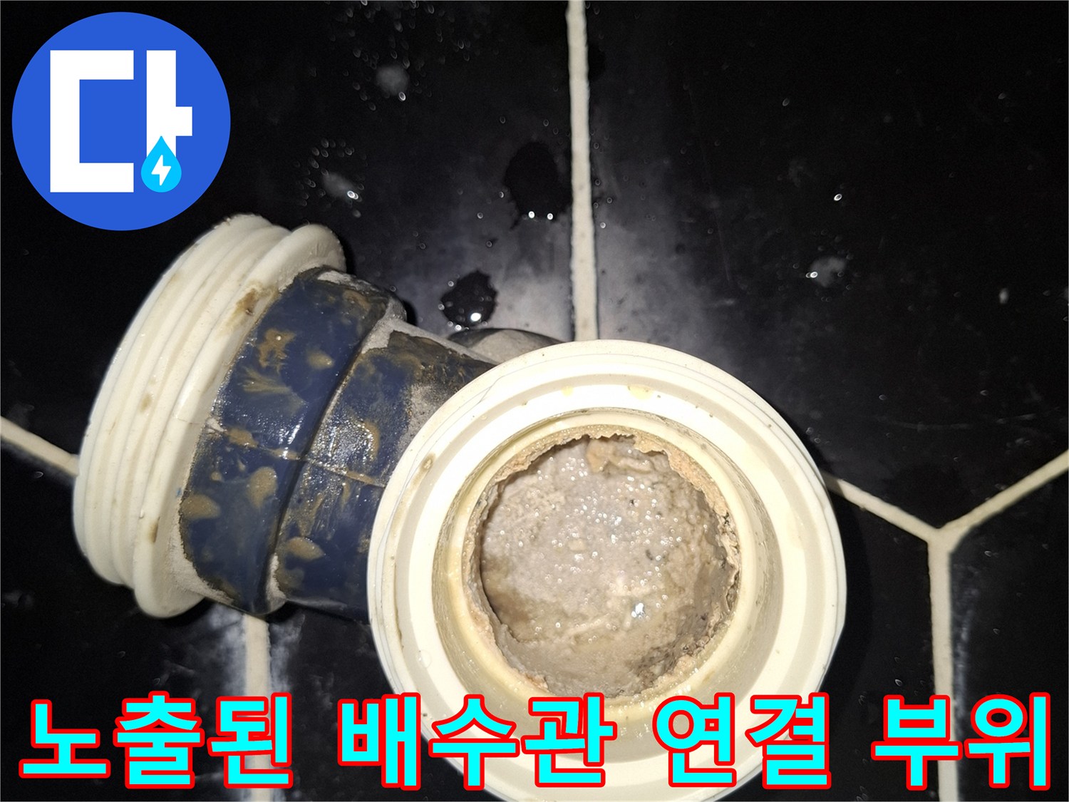 검은색 육각 타일 사이에 위치한 배수 파이프