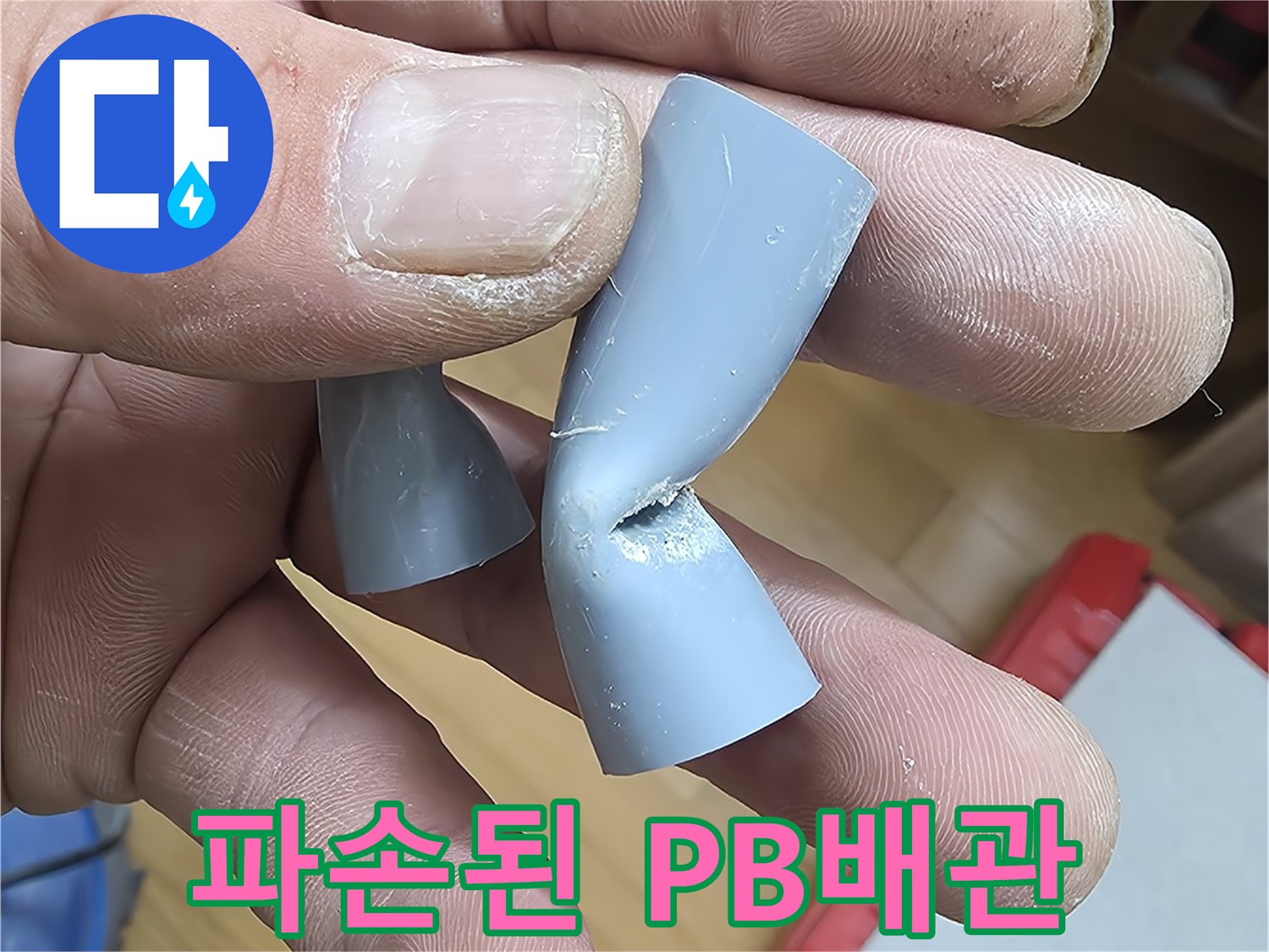 손에 들려있는-파손되어 함몰된-회색 PB 배관 엘보우 부속