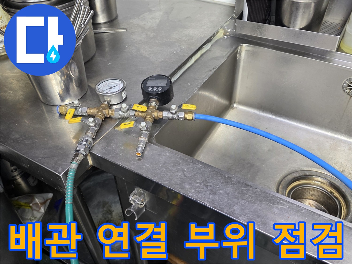 주방 배관 하단 - 파란색 호스와 금속 밸브 연결 상태