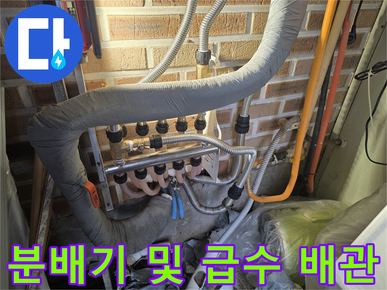 벽돌 벽면에 설치된-보온재가 감겨진 배관과 금속 분배기