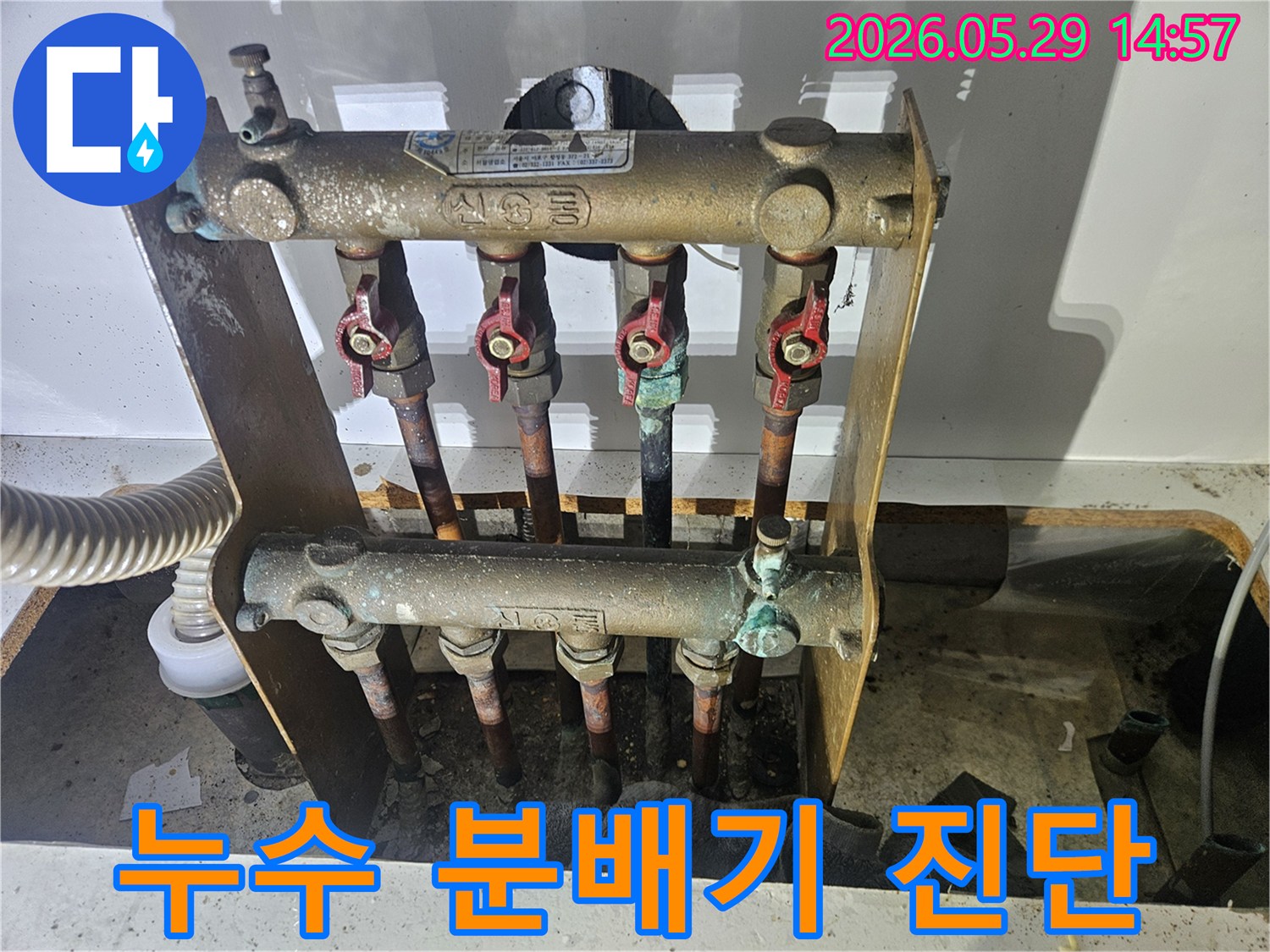 오래된 아파트의 난방 분배기에서-심각한 부식과 함께 누수 흔적이 발견되어-전문가가 교체 작업을 준비하고 있습니다.