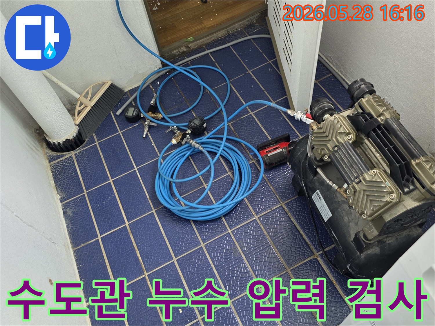 수도관-누수-원인을-찾기-위해-배관에-연결된-공압-장비와-압력-게이지-그리고-파란색-호스가-보이는-작업-현장