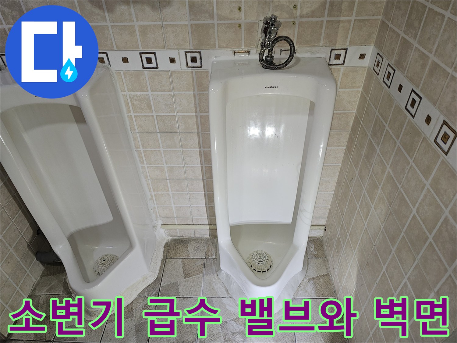 소변기에 연결된 급수 밸브와 타일 벽면의 모습입니다.