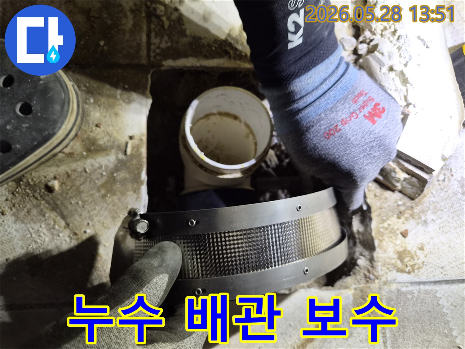 작업자가 장갑을 끼고-누수 지점의 배관에-보수 밴드를 설치하는 장면입니다