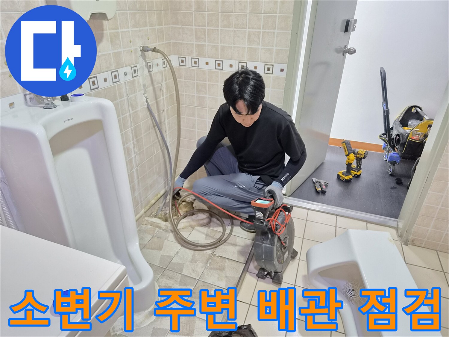 탈거된 소변기 옆으로 드러난 바닥 배관과 작업 중인 엔지니어의 모습