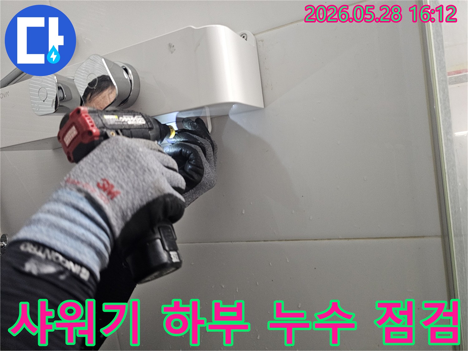 숙련된 기술자가-보호 장갑을 착용하고-전동 드라이버로-샤워기 아래쪽에서-발생한 누수를-정밀하게-조사하는-모습입니다