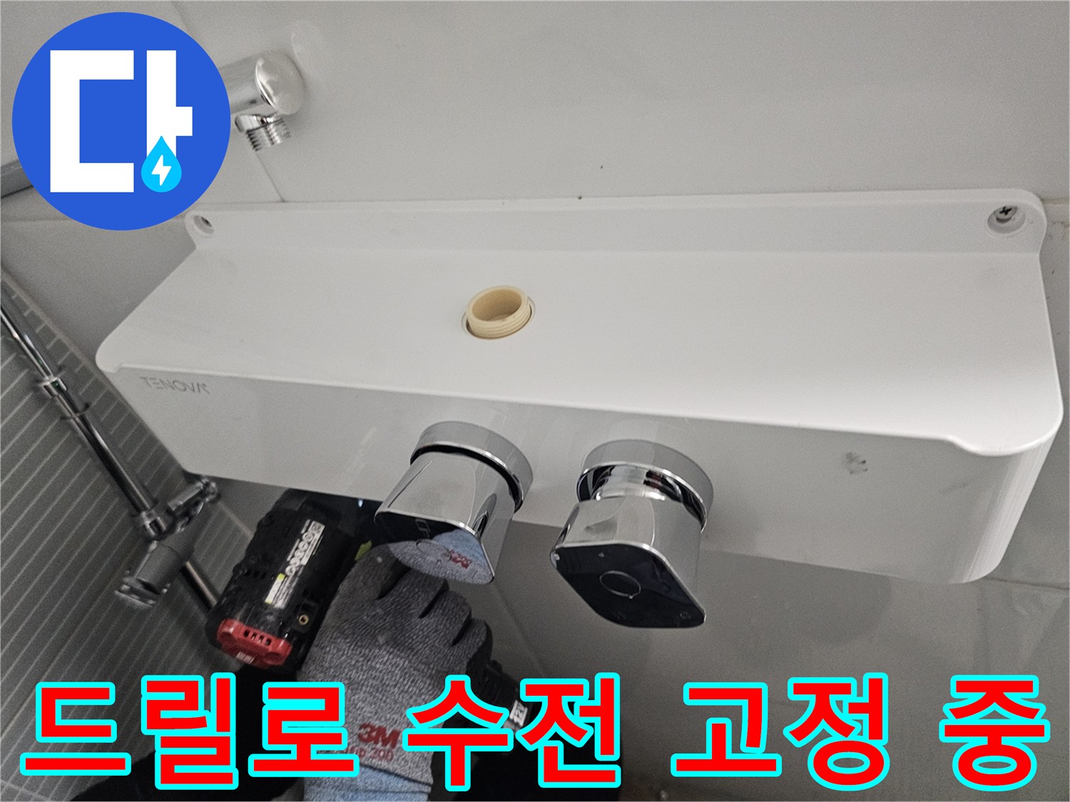 전동 드릴을 사용하여 수전 본체를 벽면에 고정하는 장면