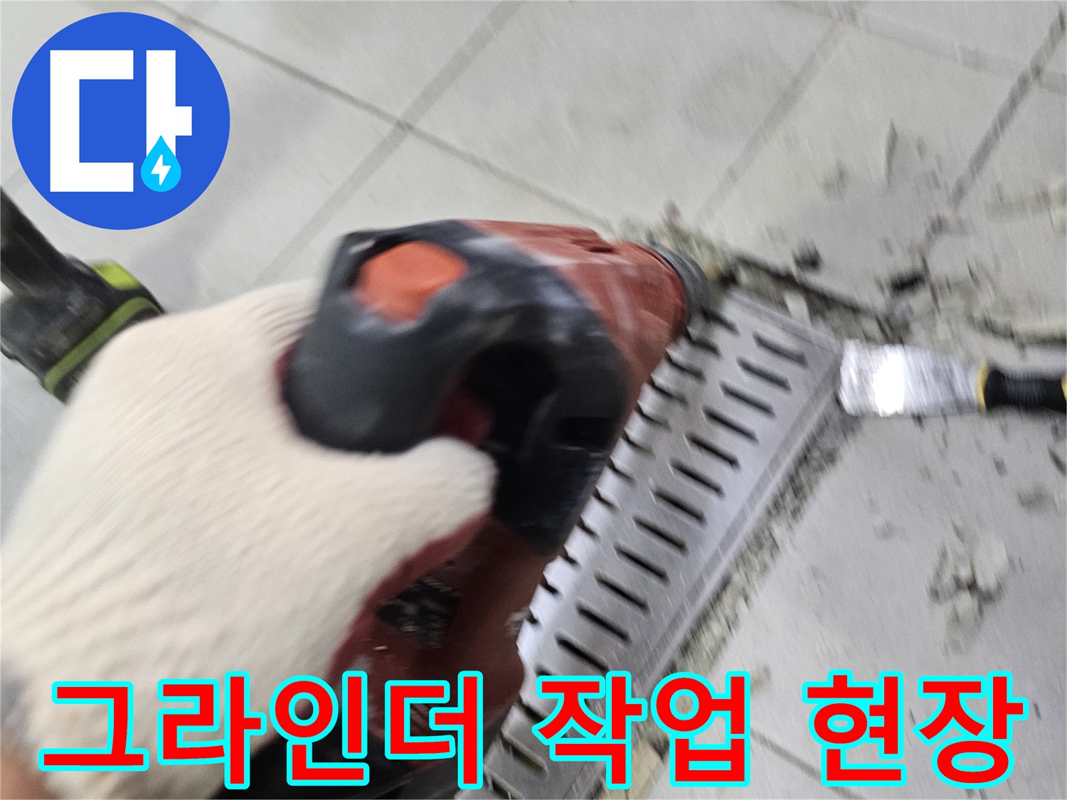 전동 드릴을 사용하여 배수 트렌치 옆 타일을 제거하는 모습