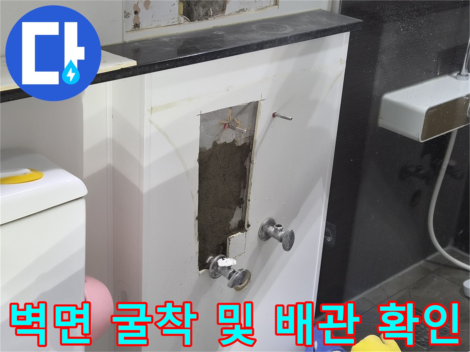 화장실 벽면을 제거하여 드러난 수도 연결 부위와 주변 환경