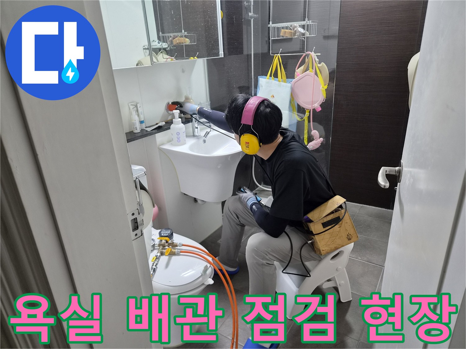 화장실 세면대 아래에서 진행 중인 수도 배관 점검 작업