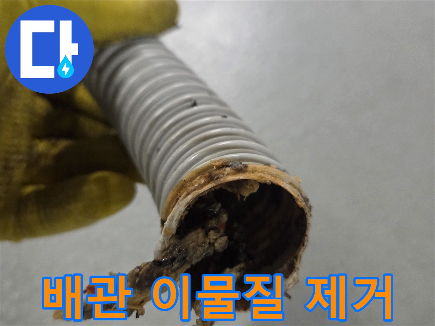 노란 장갑을 낀 손이-배관 내부에서 제거된-심각한 이물질을 보여주고 있습니다.