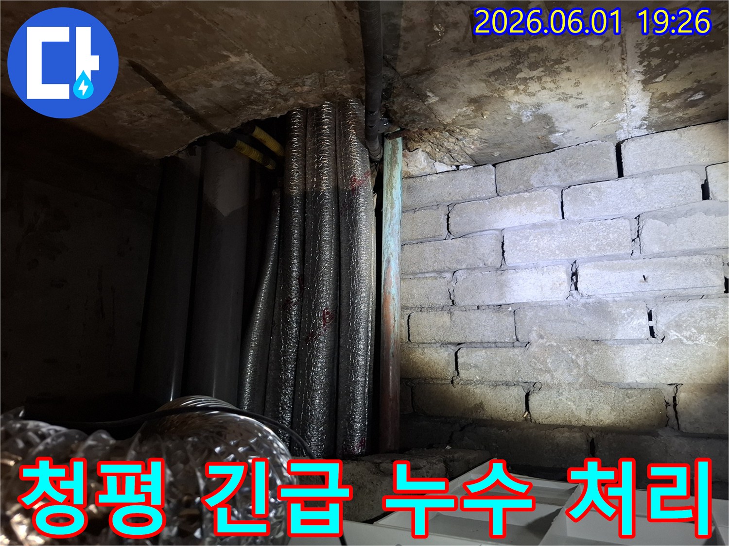 어두운 지하 공간에서-천장 배관과-벽돌 벽면의-누수 흔적을-확인하는 모습의-누수탐지 현장 사진입니다