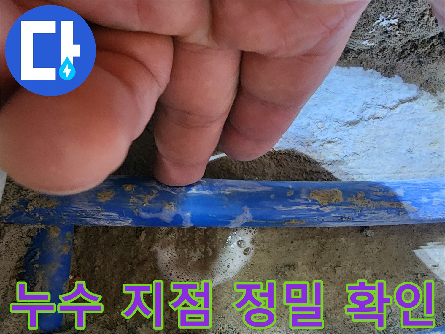 전문가의 손이-파란색 수도관의-누수 지점을 가리키며-거품으로 누수를-명확히 보여주는 사진