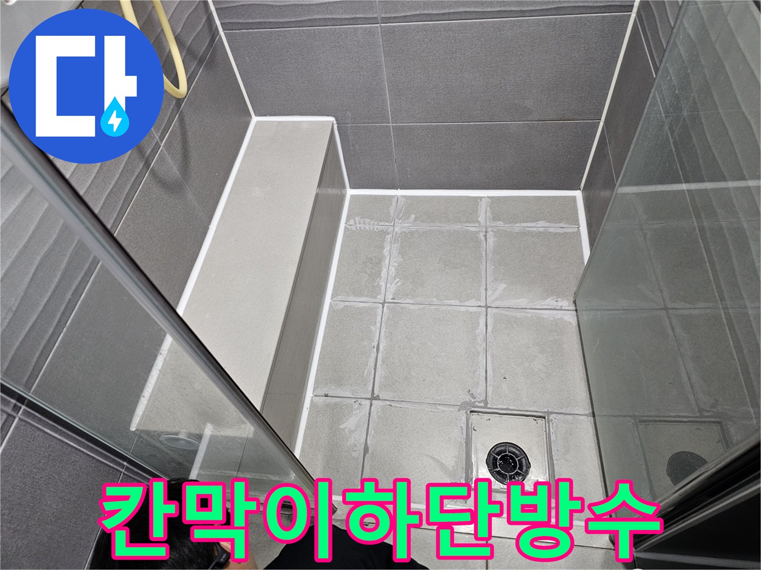 강동구 주택 욕실의 칸막이 하단 부분에-누수를 막기 위해-전문가가 방수 실리콘으로 꼼꼼하게 시공하는 모습입니다.