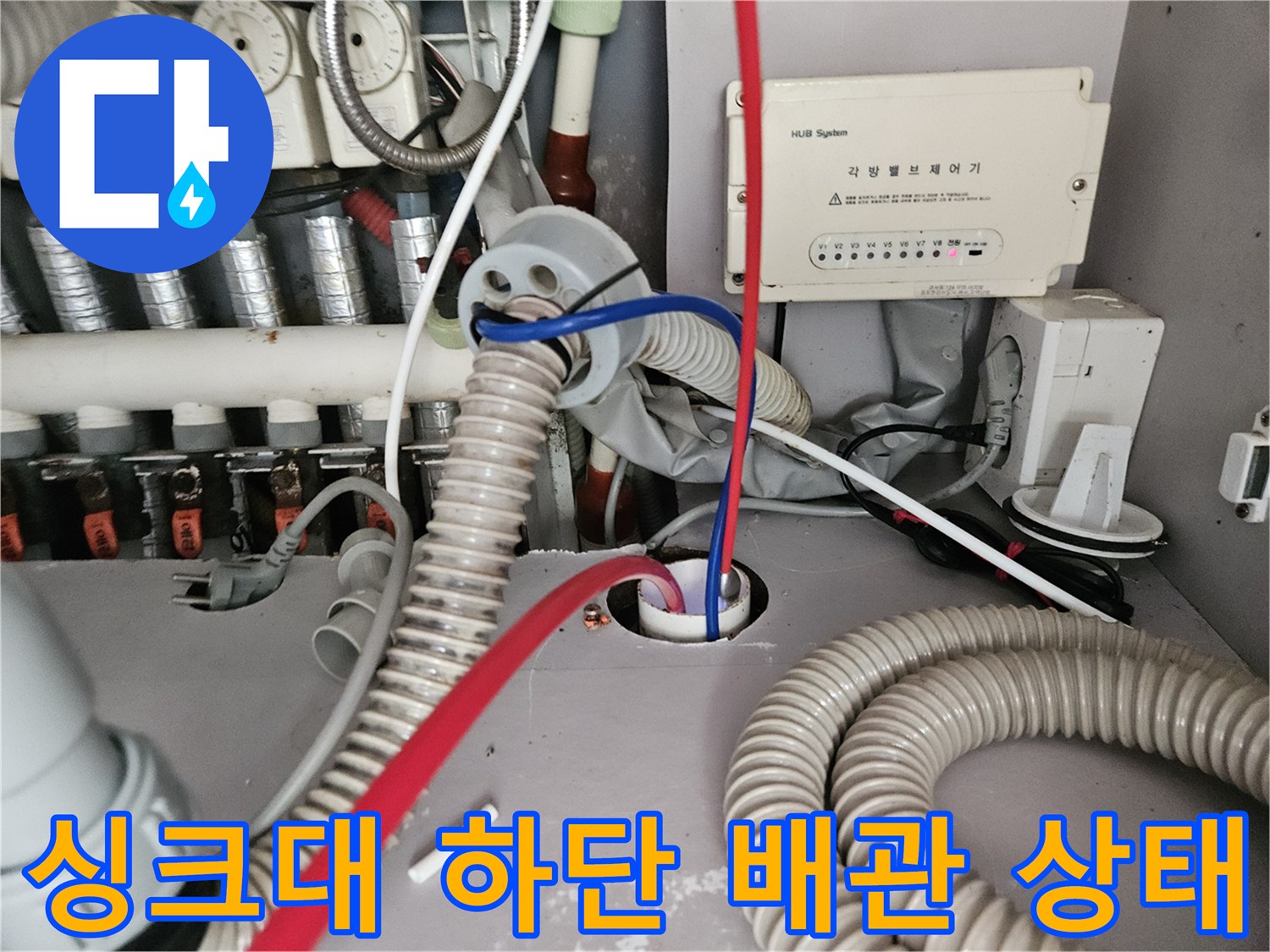 복잡한 급수 및 배수 라인이 연결된 싱크대 아래쪽 내부 사진