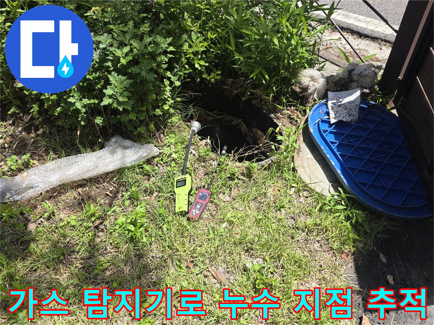 마당 맨홀 덮개 옆에서 가스식 탐지 장비를 사용하여 배관 상태를 확인 중