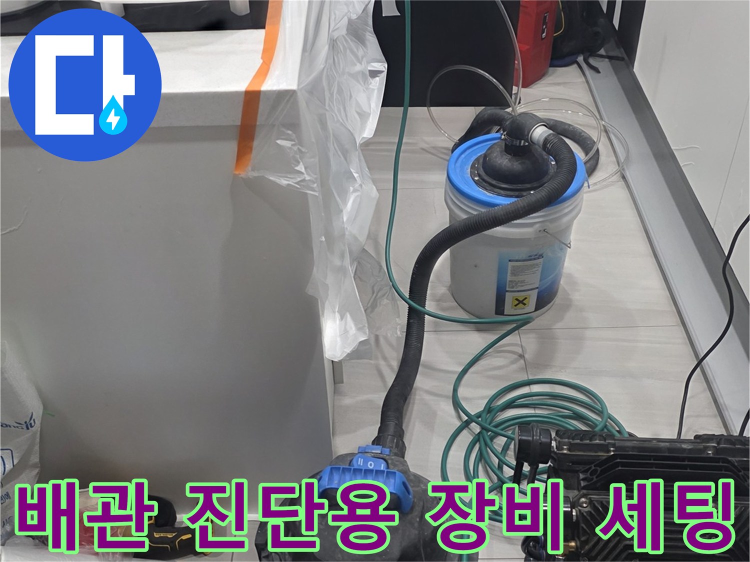 싱크대 아래 작업 공간에 놓인 압력계와 청소 도구들