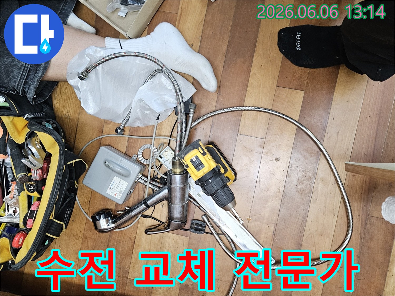 전문가가 누수 탐지 및 수리를 위해-가져온 공구 가방-전동 드릴-그리고 교체용 수도 부품들이 바닥에 놓여 있습니다.