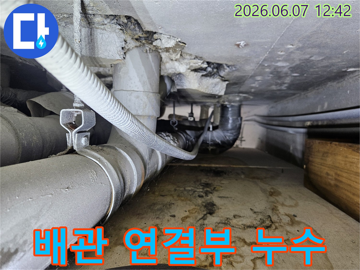 배관 연결 부위에서 물이 새어 나와-바닥에 물자국과-습기가 가득한-누수 현장의 모습입니다.
