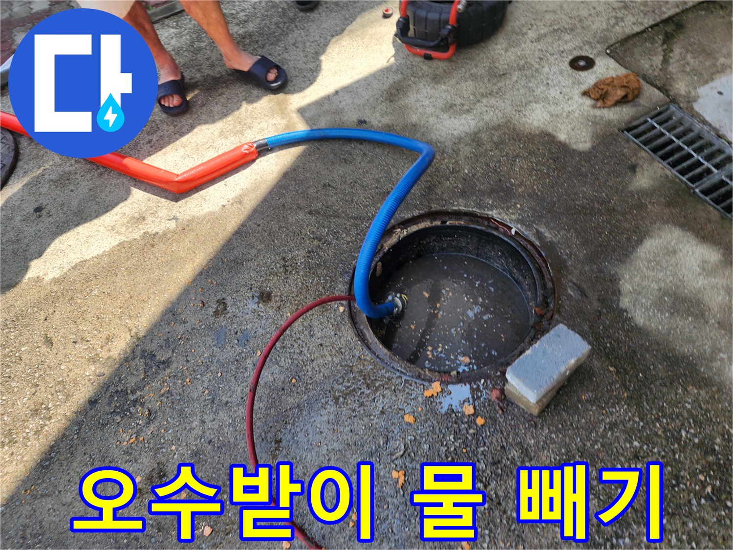 오수받이 구멍에 꽂힌 배수 호스와 주변 작업 환경입니다.