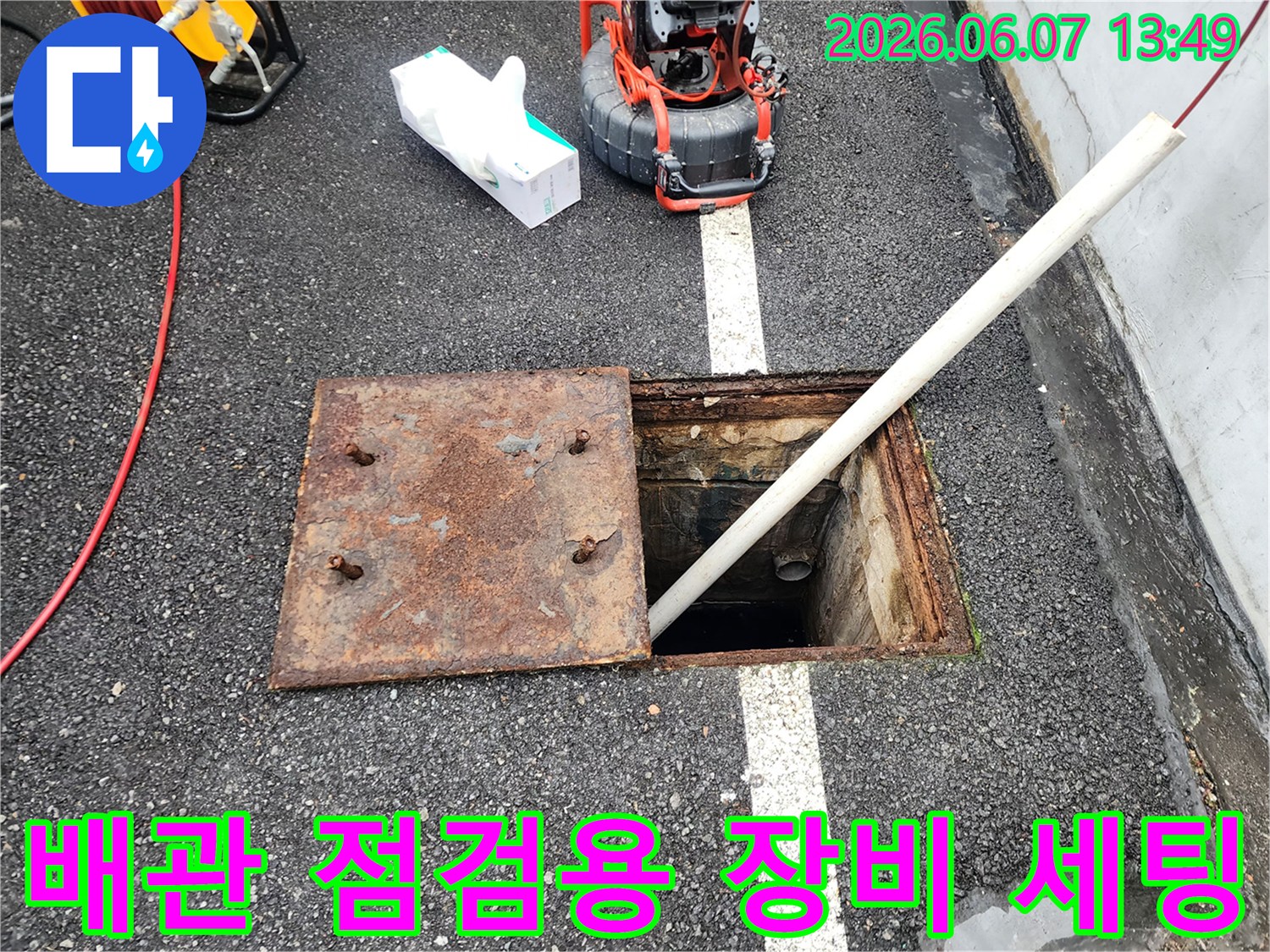 맨홀 근처에 놓인 배관 작업용 전문 장비와 내시경 케이블