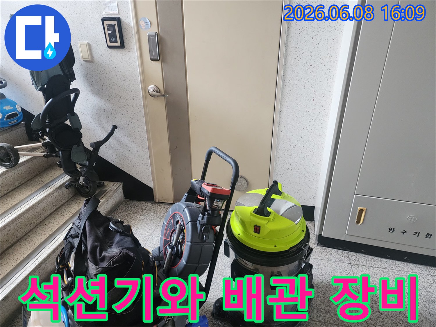 계단 옆 복도에 놓인 노란색 석션기와 작업 도구들