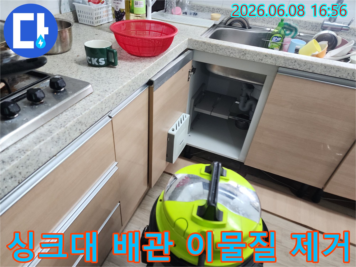 싱크대 하부장 내부의 노출된 배수관과 작업용 장비입니다.