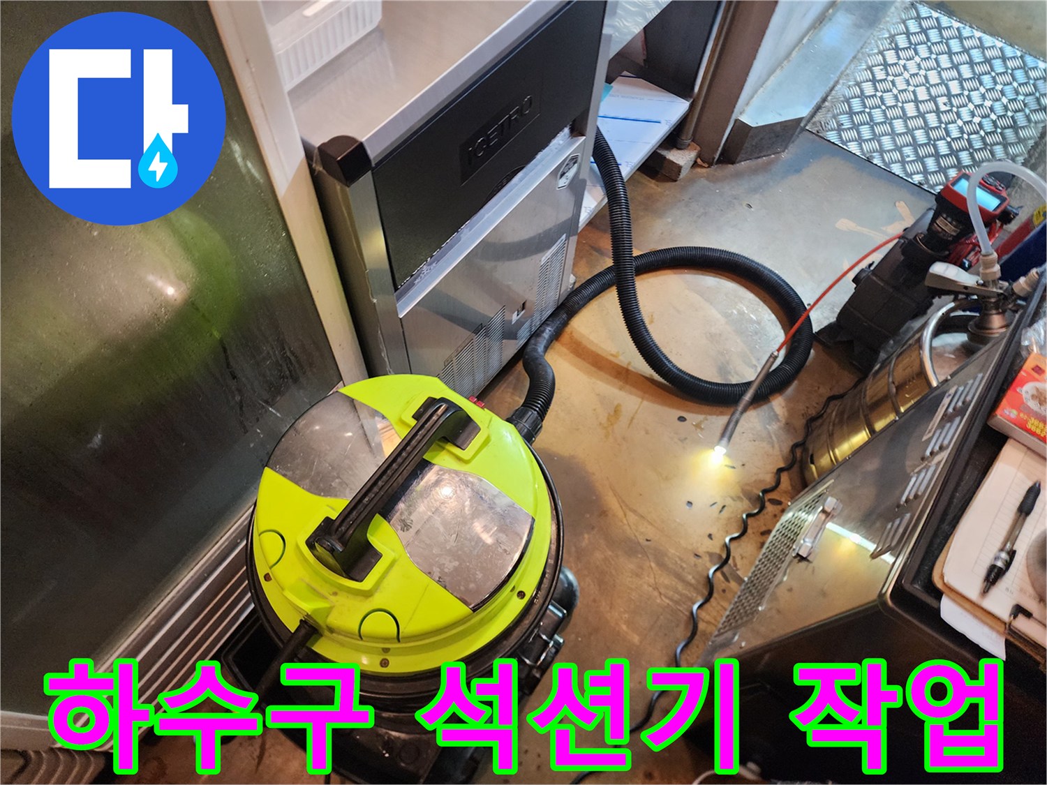 바닥에 놓인 노란색 산업용 석션기와 검은색 호스 연결