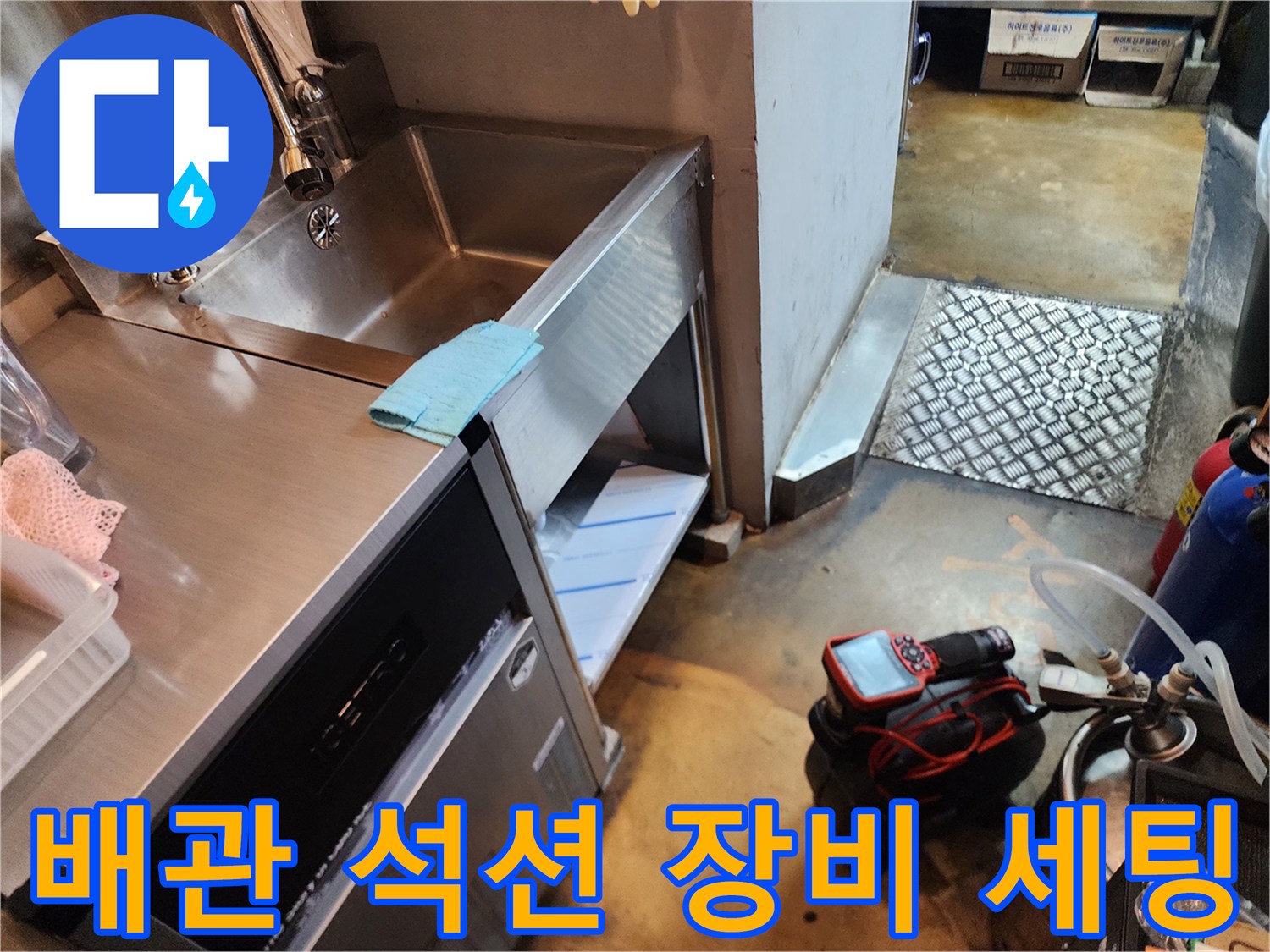 스테인리스 싱크대 밑에 배치된 빨간색 석션기와 작업 도구들